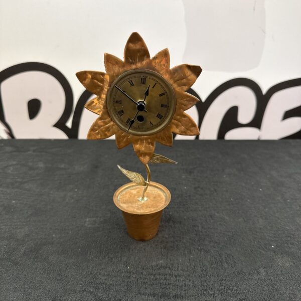 Vintage copper sunflower quartz clock on a dark surface.