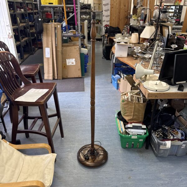 Full view of a vintage wooden standard lamp in a cluttered room.