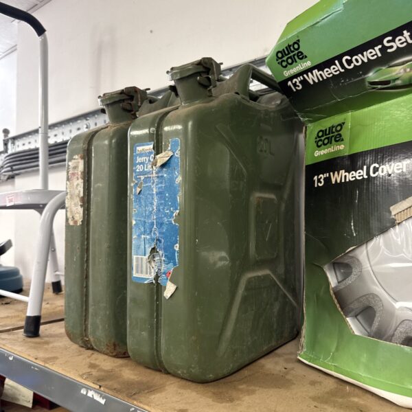 Two vintage 20L metal Jerry cans with faded paint.