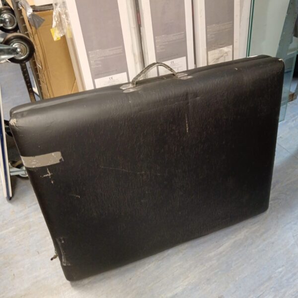 Black folding massage table showing signs of wear.