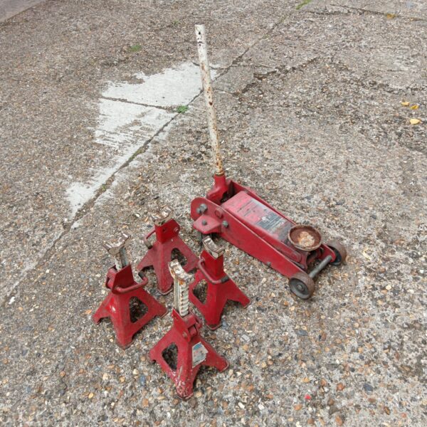 Red trolley jack and four axle stands for vehicle maintenance.