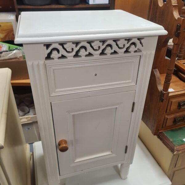White ornate bedside cabinet with a single door and decorative detailing.