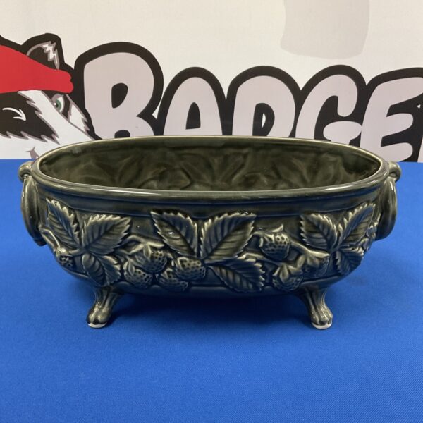 Vintage porcelain strawberry planter with detailed texture and green leaves.