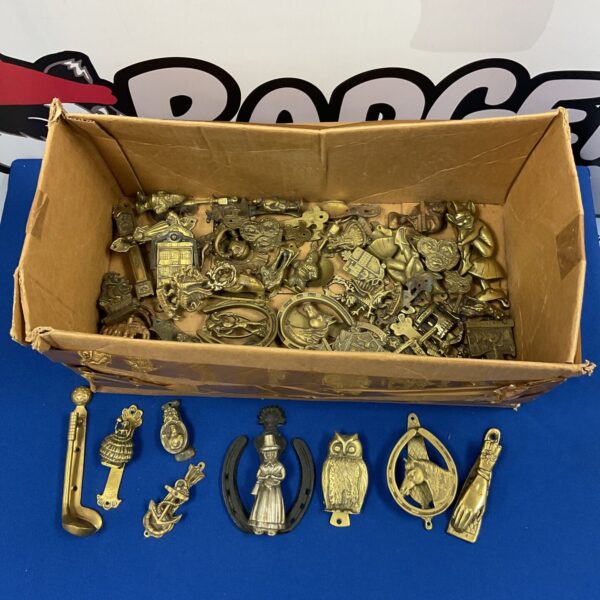 Large collection of antique brass door knockers on display.