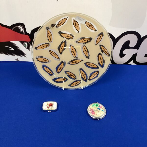Vintage decorative glass plate with two compact cases displayed.
