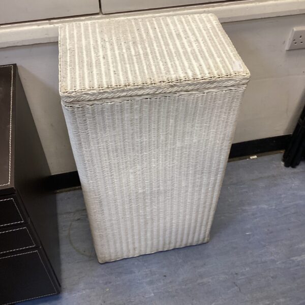 Vintage white wicker wash bin for laundry or storage.
