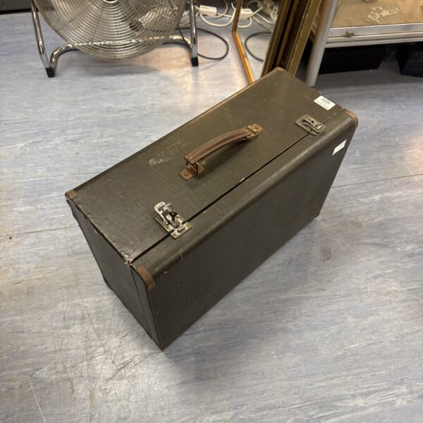 Vintage sewing machine case with a worn exterior and handle.