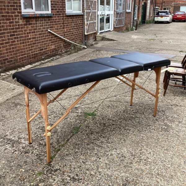 Portable folding massage table with wooden frame.