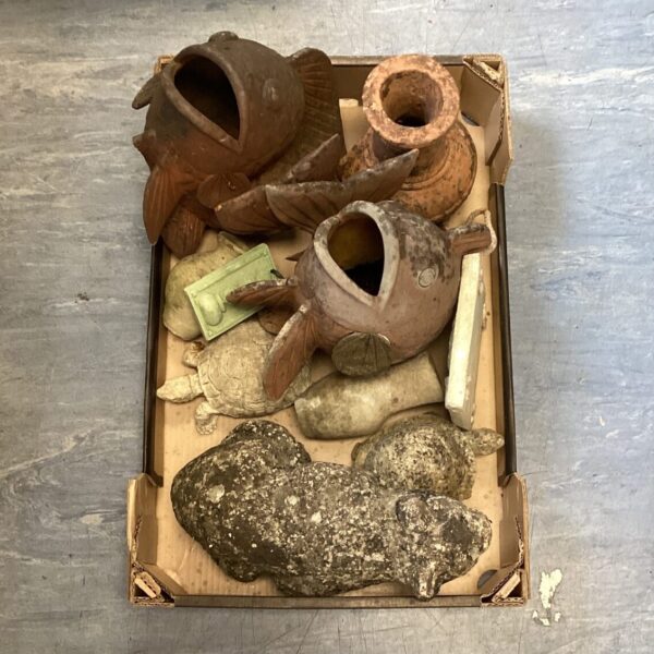 Rustic garden stone ornaments and terracotta fish planters for outdoor decor.