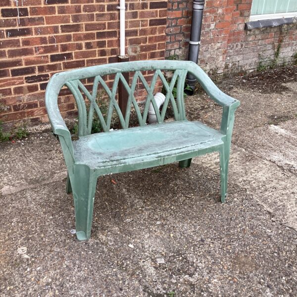 Weathered plastic garden bench in a garden setting.