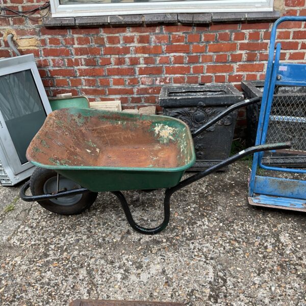 Rusty vintage metal wheelbarrow in a garden setting.