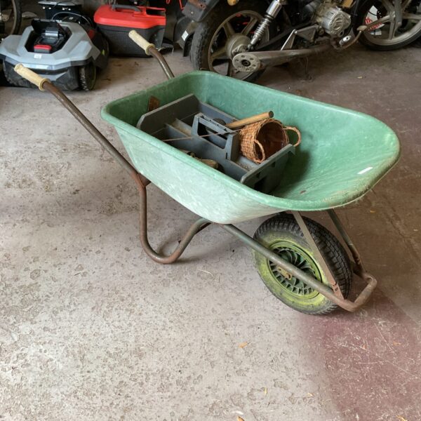 Used plastic garden wheelbarrow with tools inside.