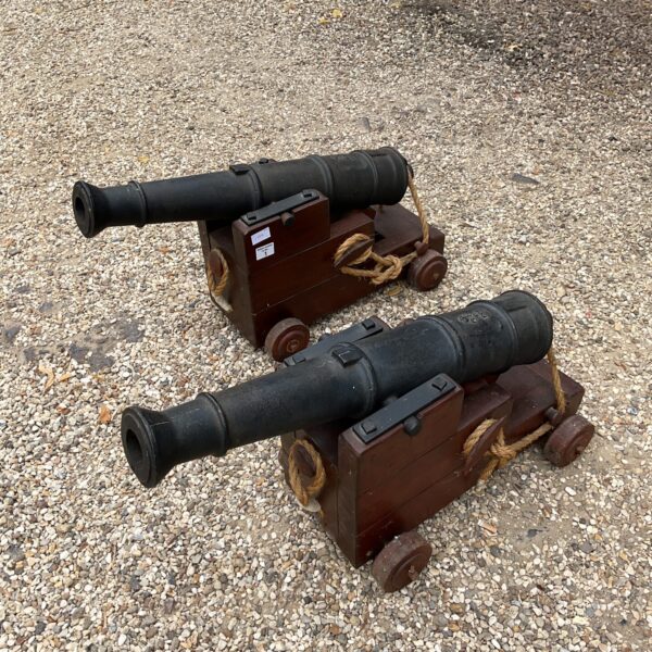 Pair of reproduction cannons on display in a garden setting.