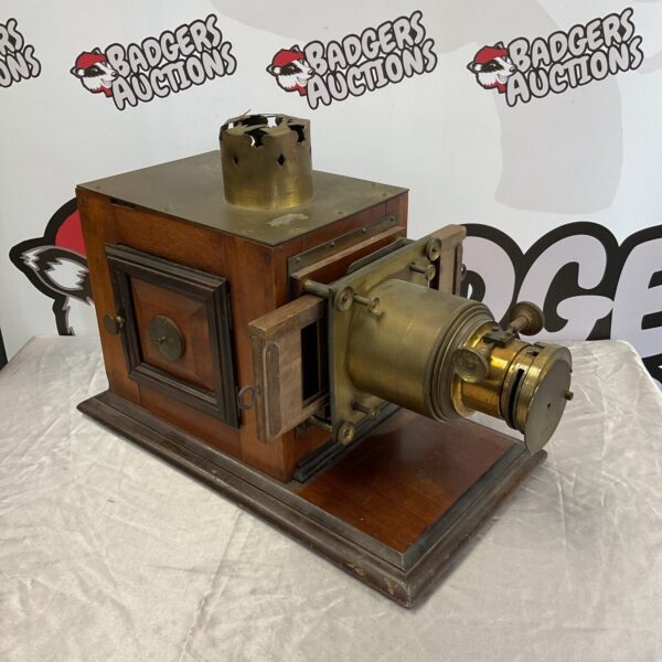 Antique Victorian magic lantern projector with brass lens and wooden base.