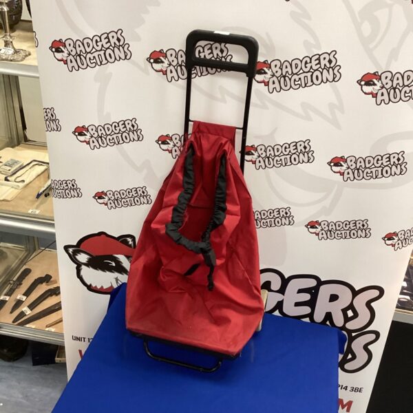 Red folding shopping trolley with extending handle for easy portability.
