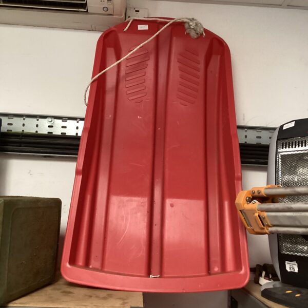 Red plastic snow sledge for winter fun on snowy hills.