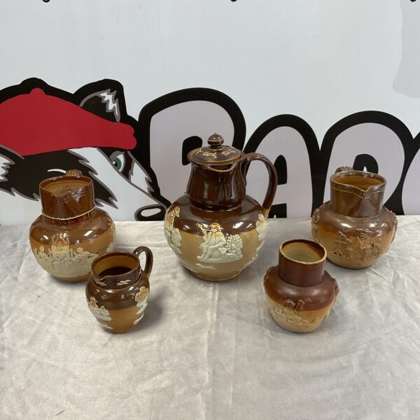 Lot of five antique Royal Doulton Lambeth ware jugs on display.
