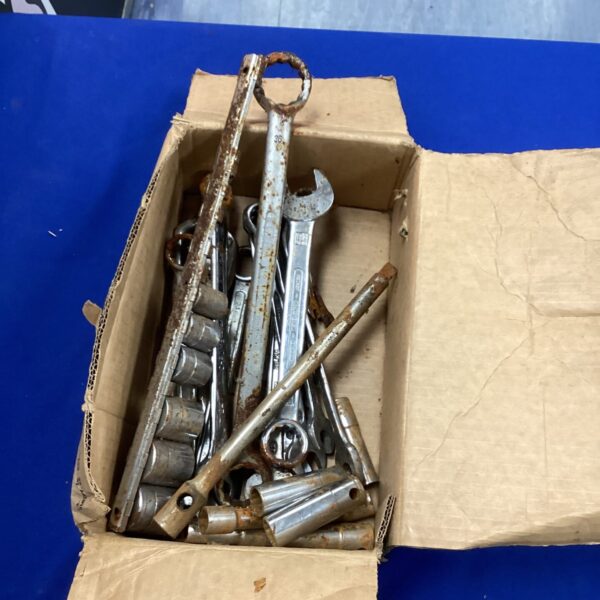 Mixed tool lot in a cardboard box, including wrenches and sockets.
