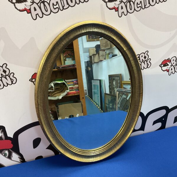 Antique gilt framed oval mirror for wall decoration.