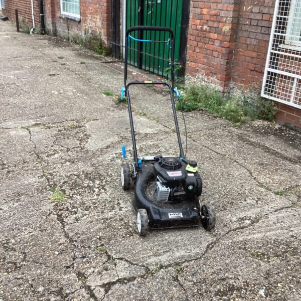 Vintage Mac Allister lawn mower in a garden setting.