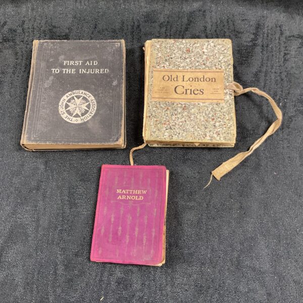 Stack of three vintage books including First Aid and Old London Cries.