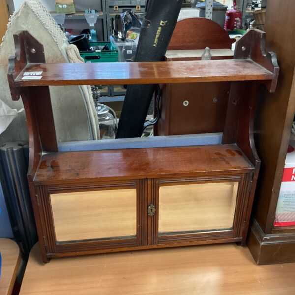 Antique wooden display case with a single door and shaped pediment.