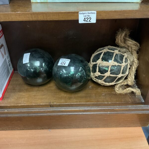 Three antique glass net floats displayed for sale.