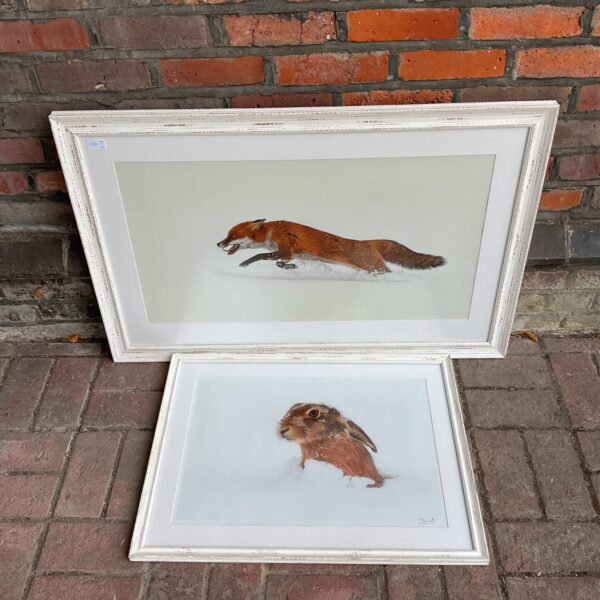 Framed fox and rabbit prints in a snowy winter scene.