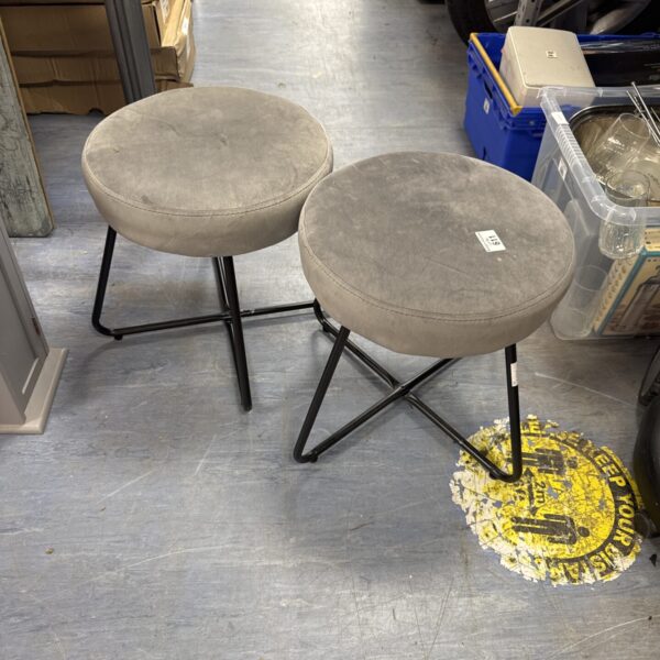 Two grey velvet stools with black metal legs.