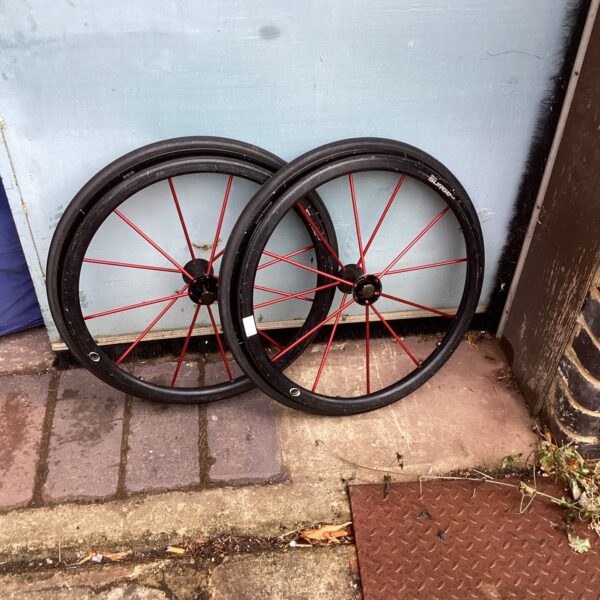 Two silver and red spoked wheelchair wheels for mobility aid repair.