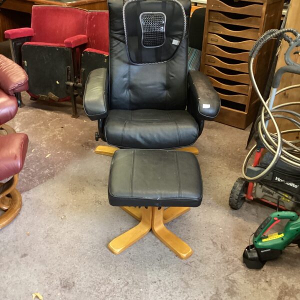Black leather reclining chair with footstool in a room setting.
