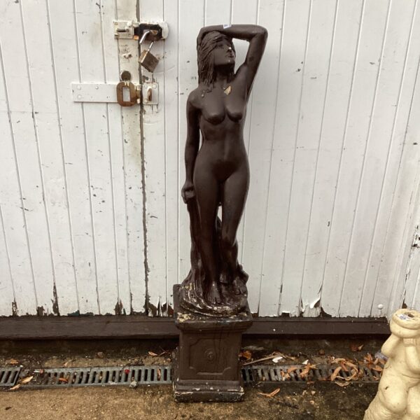 Weathered antique garden statue of a nude female on a plinth.