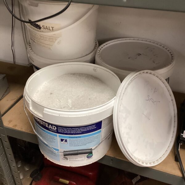 Four plastic tubs filled with rock salt for winter de-icing.
