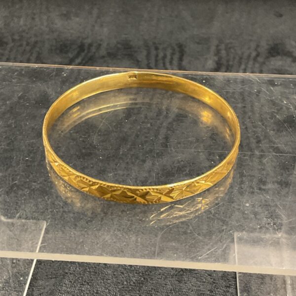 Close-up of a vintage gold bracelet with geometric patterns.