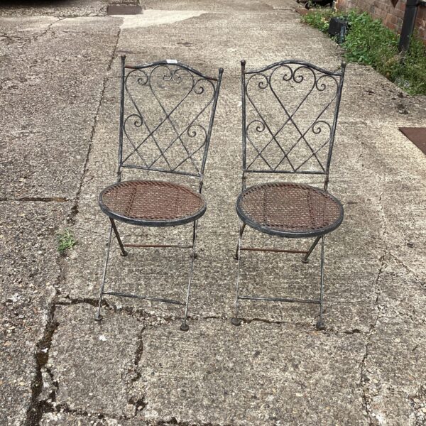 Pair of vintage metal garden chairs in a garden setting.