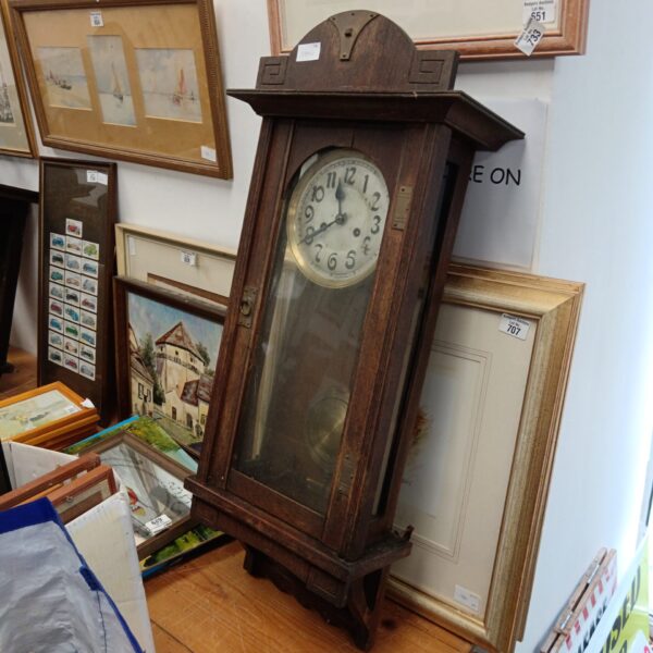 Antique oak wall clock with Roman numeral face and pendulum.