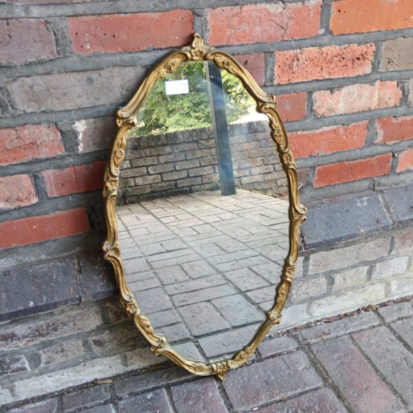 Ornate gilt framed French boudoir mirror for wall decoration.