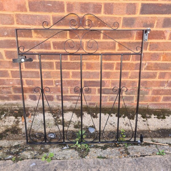 Antique wrought iron gate with decorative scrolling design.