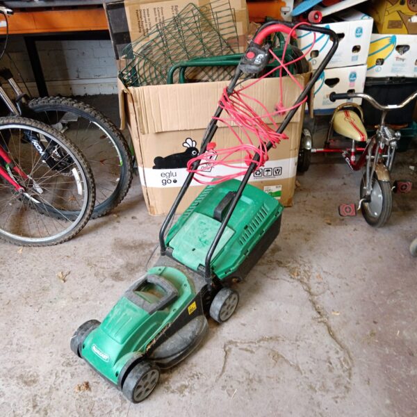 Vintage Qualcast electric lawn mower in a garden setting.