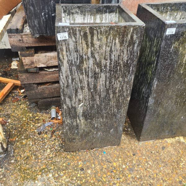 Large granite stone planter with weathered texture in a garden setting.