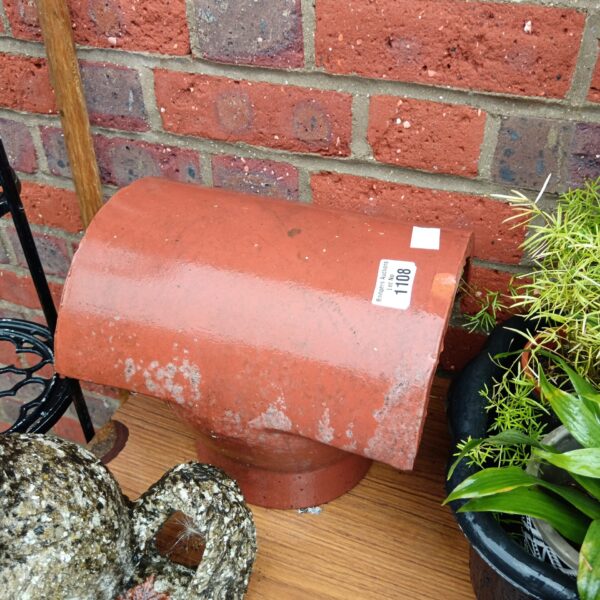 Vintage terracotta chimney cowl in a garden setting.