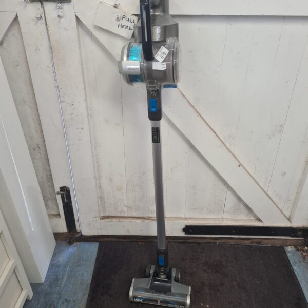 Vax Blade 32v cordless vacuum cleaner against a door.