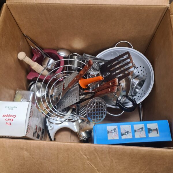 Overhead view of a cardboard box filled with mixed stainless steel kitchenware.