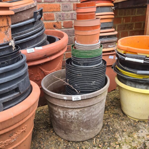 Assorted plastic garden pots stacked for storage in a garden setting.