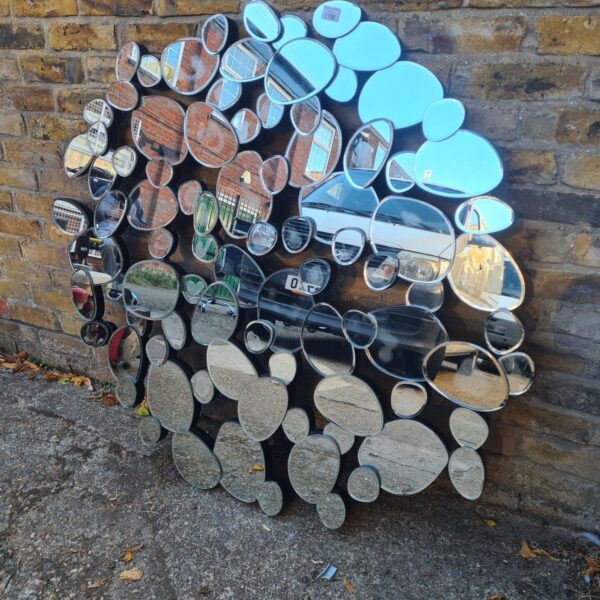 Large pebble mirror with mosaic design on a wall.
