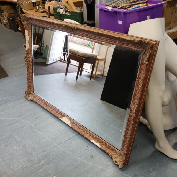 Large antique overmantle mirror with ornate gilt frame and bevelled edge.