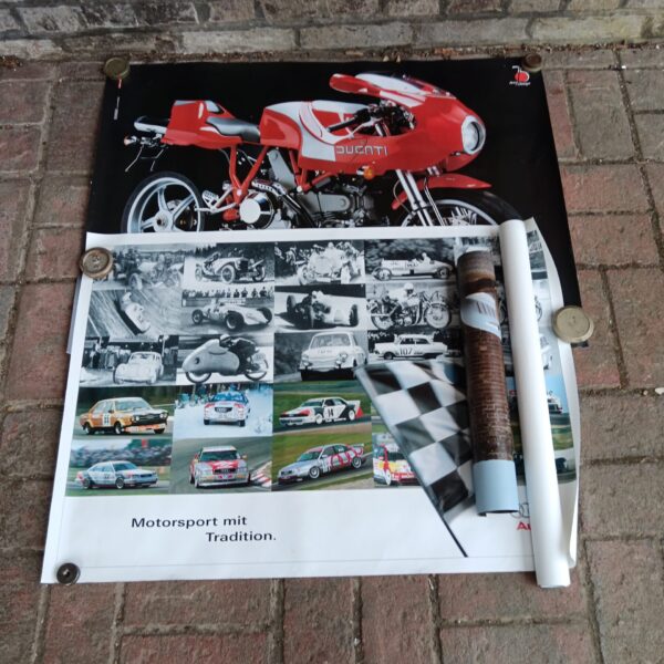 Vintage Auto Union and Audi racing posters displayed on a brick wall.