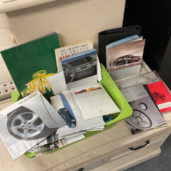 Collection of vintage car owner’s manuals including Mercedes and Land Rover.