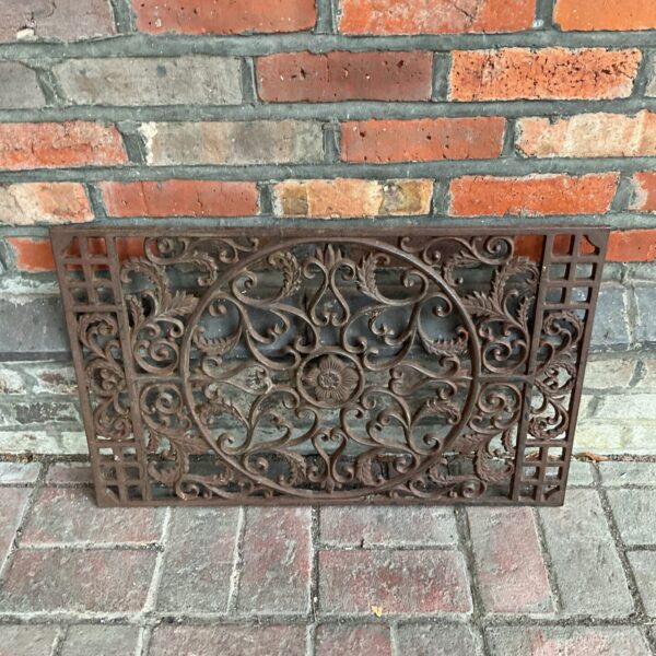 Antique cast iron door mat with floral design for garden or entryway.