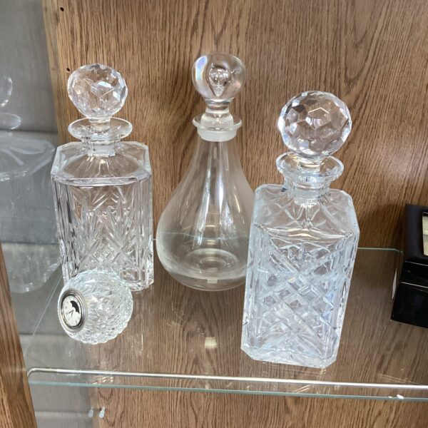 Vintage crystal decanters and glass clock on display.